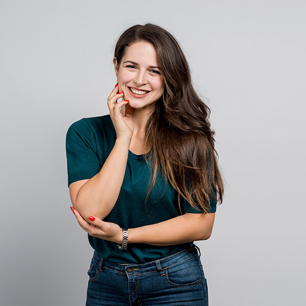 Een lachende vrouw met lang donker haar tegen een grijze achtergrond