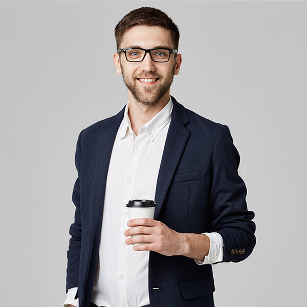 Een man met bril en baard in colbert, met een koffiebeker in zijn hand